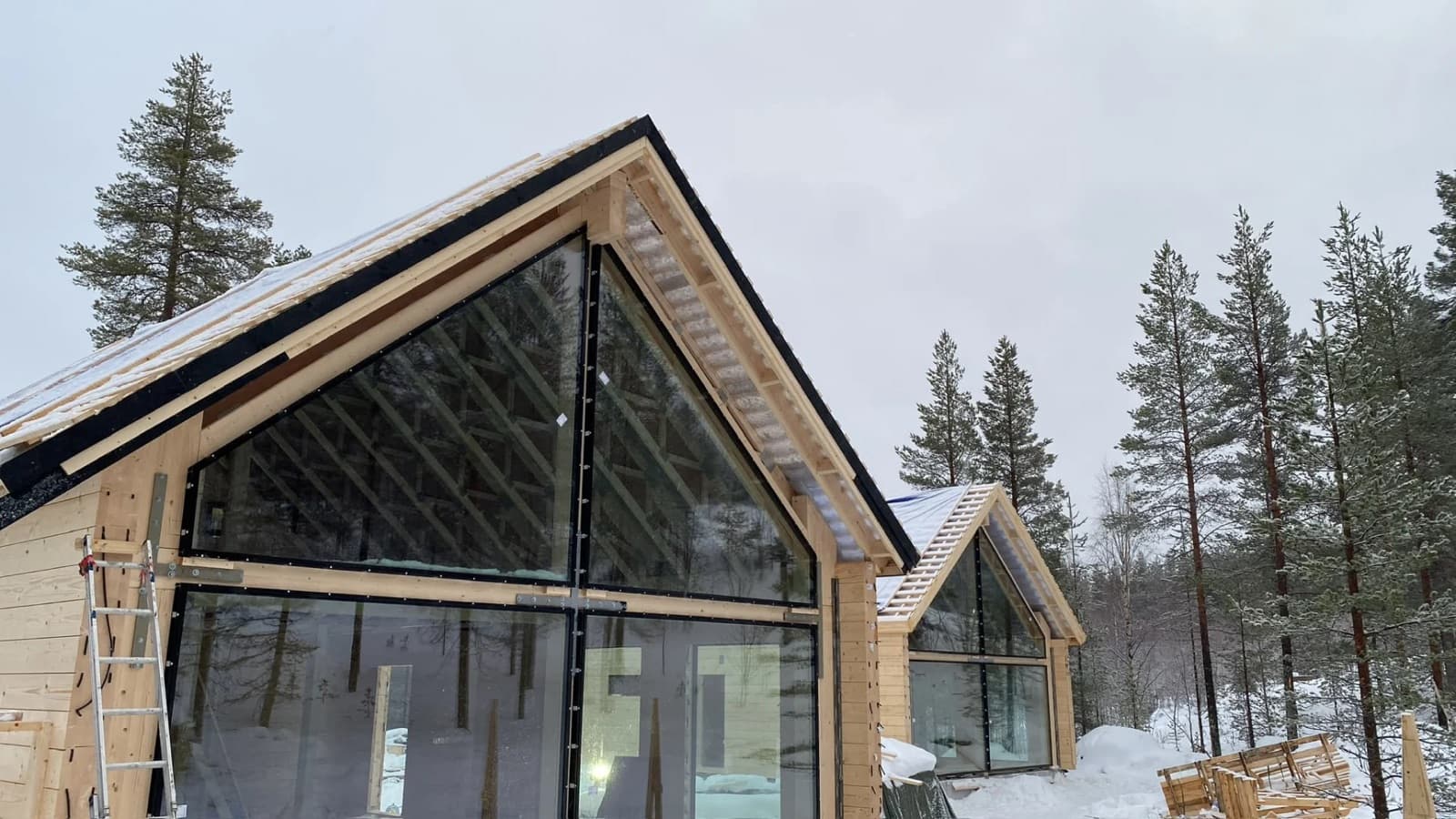 Rakenteilla oleva puutalo lumisessa metsämaisemassa