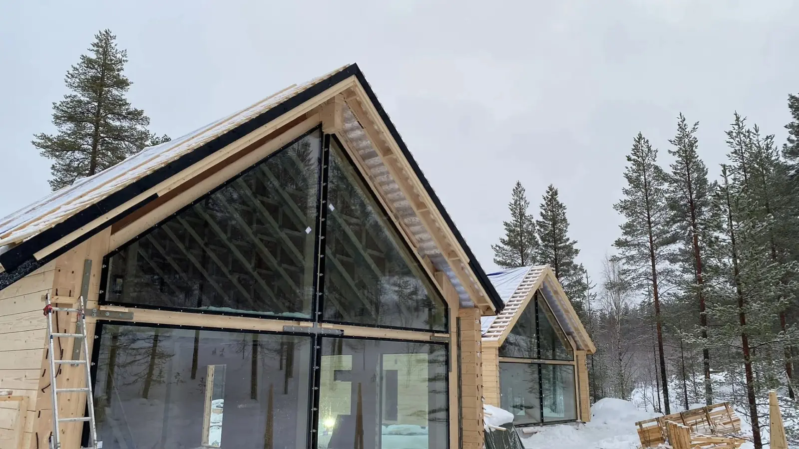 Rakenteilla oleva puutalo lumisessa metsämaisemassa